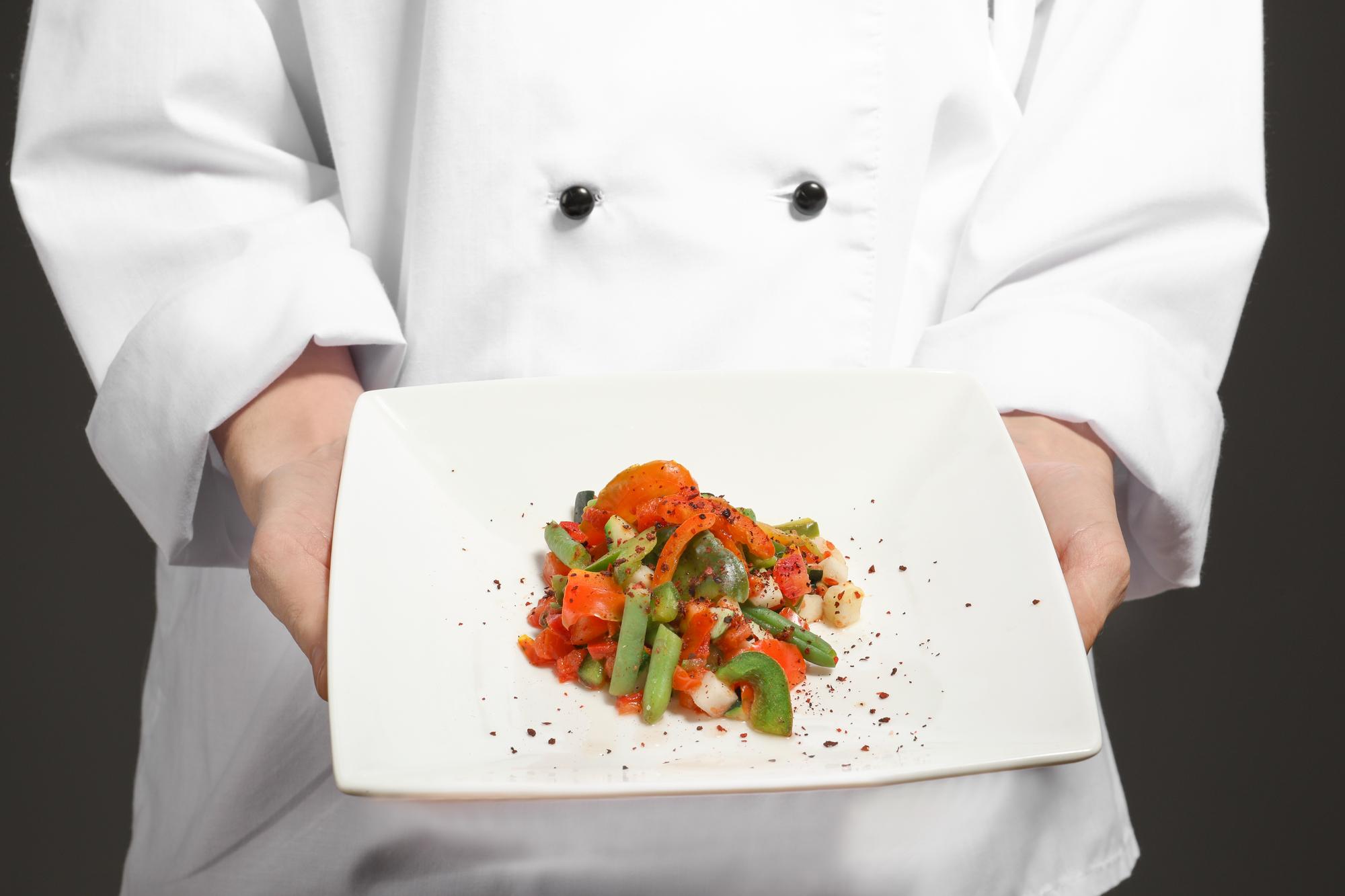 Chef arranging a plated dish in modern kitchen